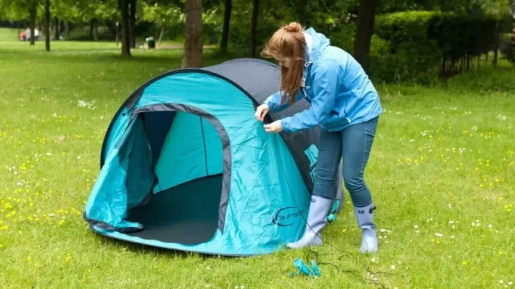 Mulher montando barraca de camping em gramado
