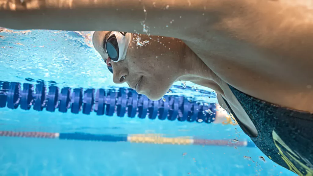 atleta nadando em piscina com óculos de natação