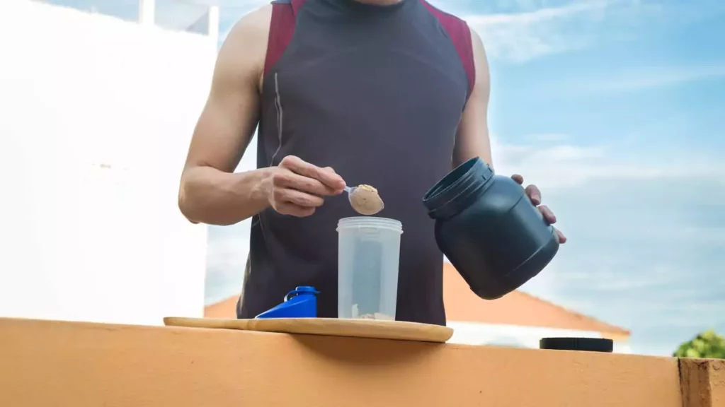 Homem preparando shake de whey hidrolisado em cima de mesa